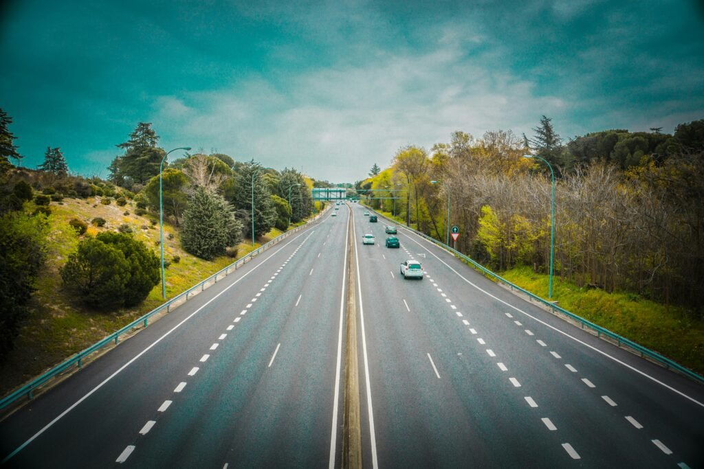 Aerial view of an open highway surrounded by trees and clear skies, perfect for travel.