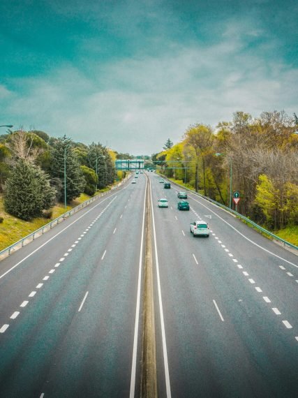 Aerial view of an open highway surrounded by trees and clear skies, perfect for travel.