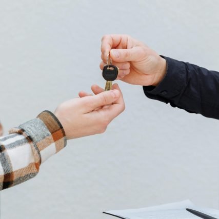 Close-up of hands exchanging car keys, symbolizing a business transaction.